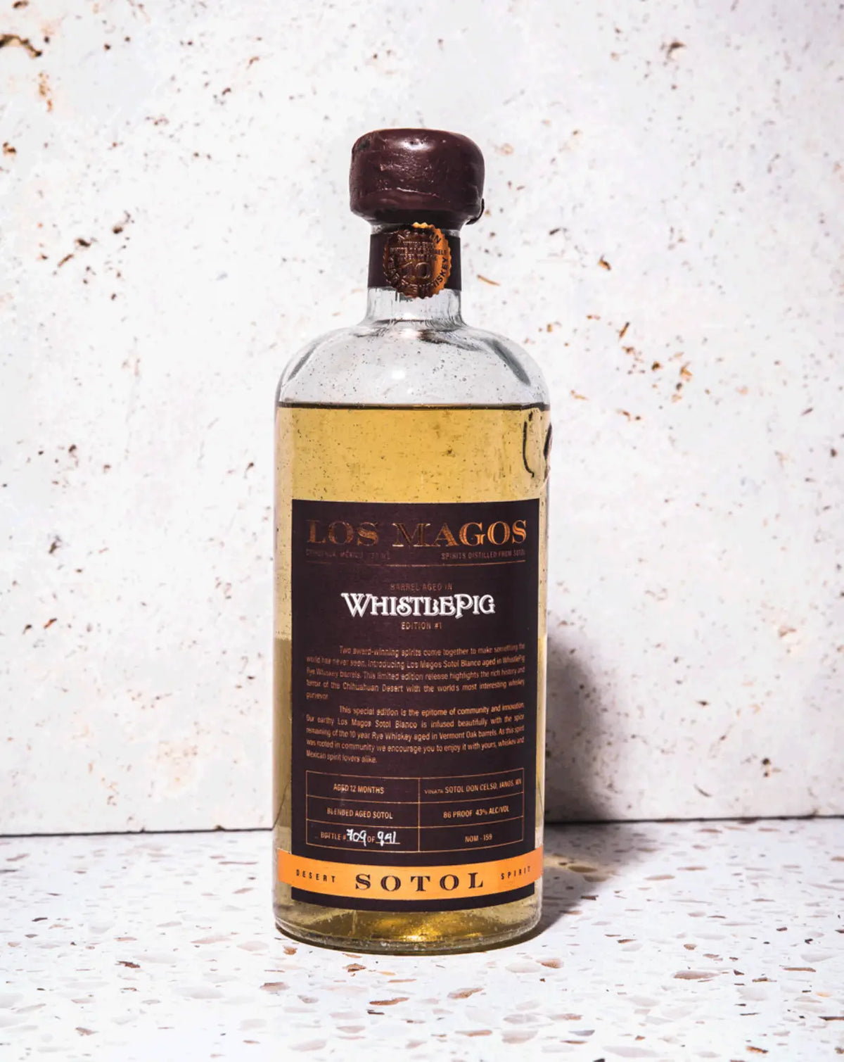 Los Magos Sotol WhistlePig Edition bottle on a speckled stone surface