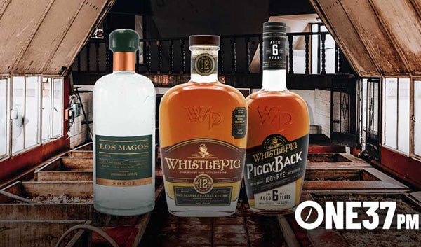 Los Magos Sotol beside two WhistlePig whiskey bottles inside a barn
