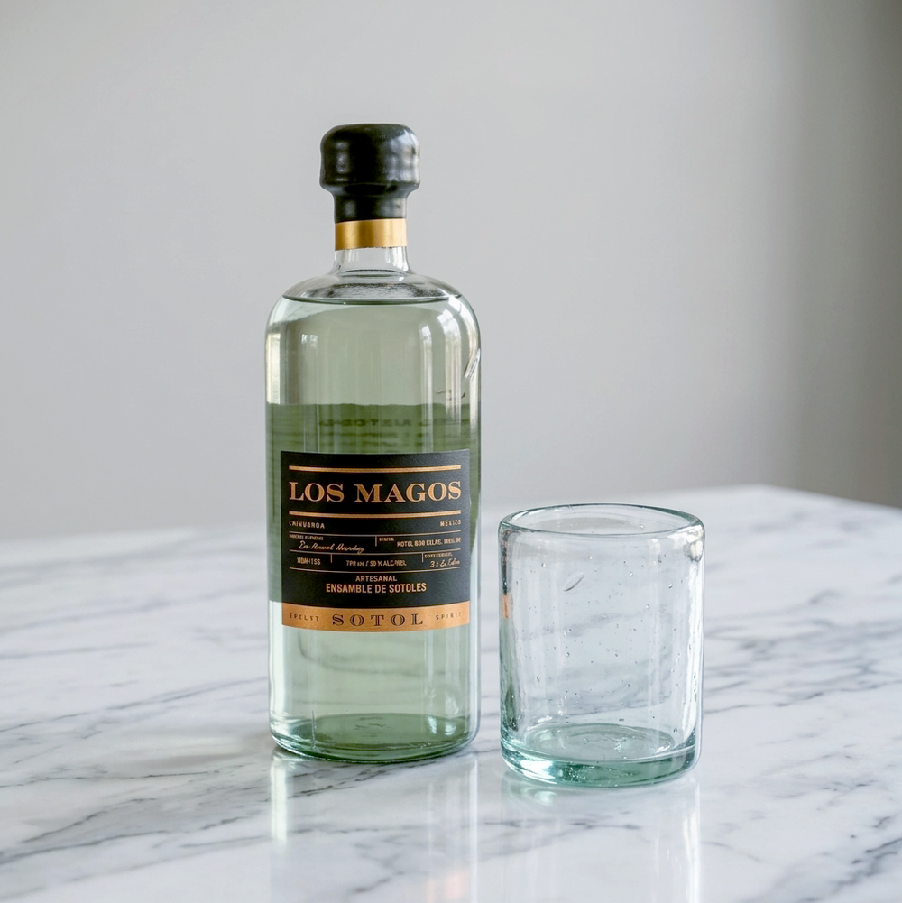 Los Magos Sotol Blanco bottle next to the hand-blown Los Magos rocks glass on marble