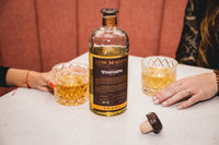 Los Magos WhistlePig Edition #1 sotol poured into two cut crystal rocks glasses, with the wax-dipped cork resting on the table